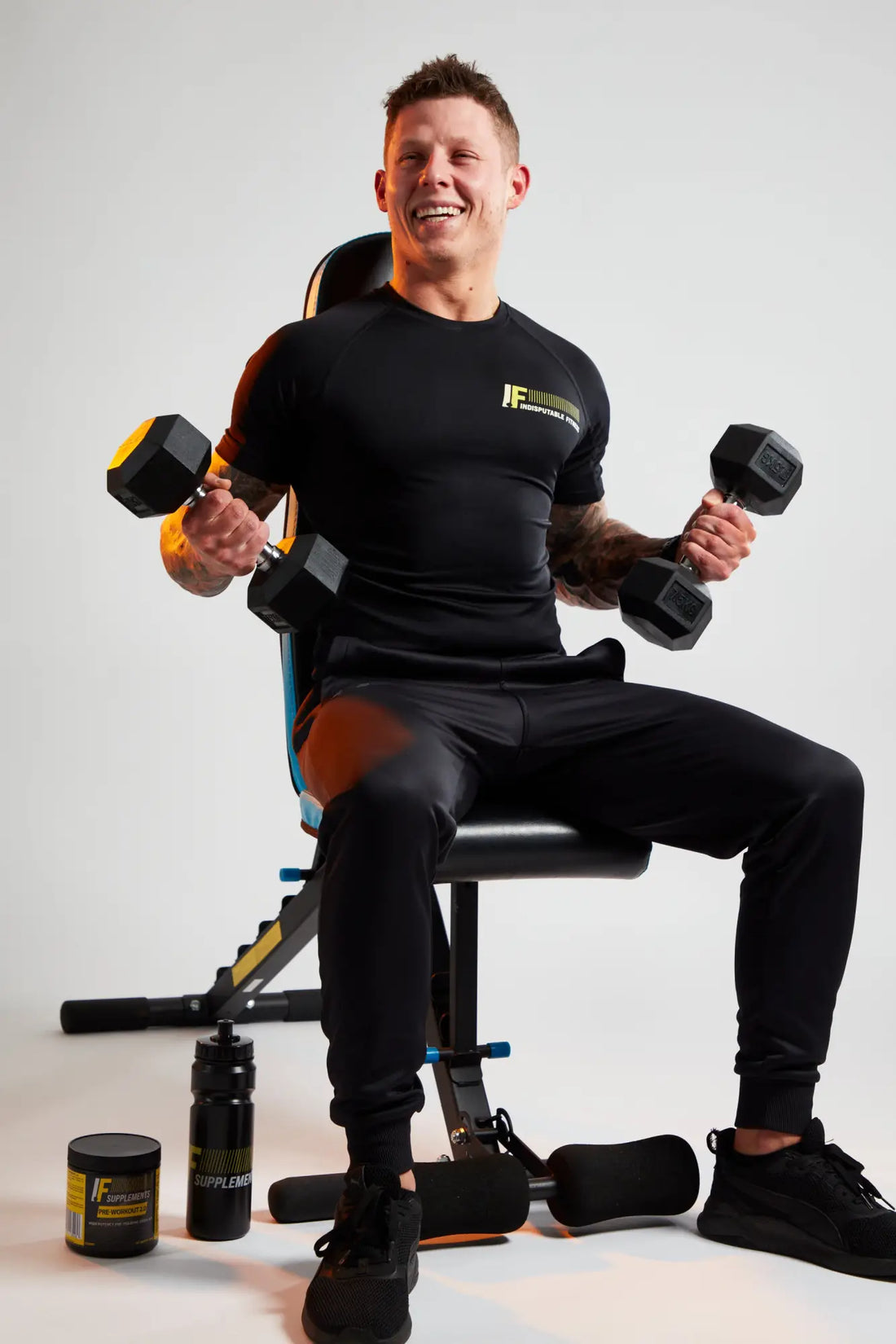 Man lifting dumbbells on weight bench during legs training split for balanced physique