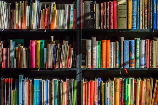 Colorful shelves of books including Atomic Habits and the 4-Hour Body for a growth mindset