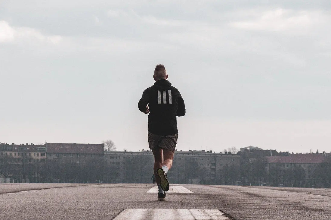Man running in Adidas hoodie demonstrating runner’s high during consistent training