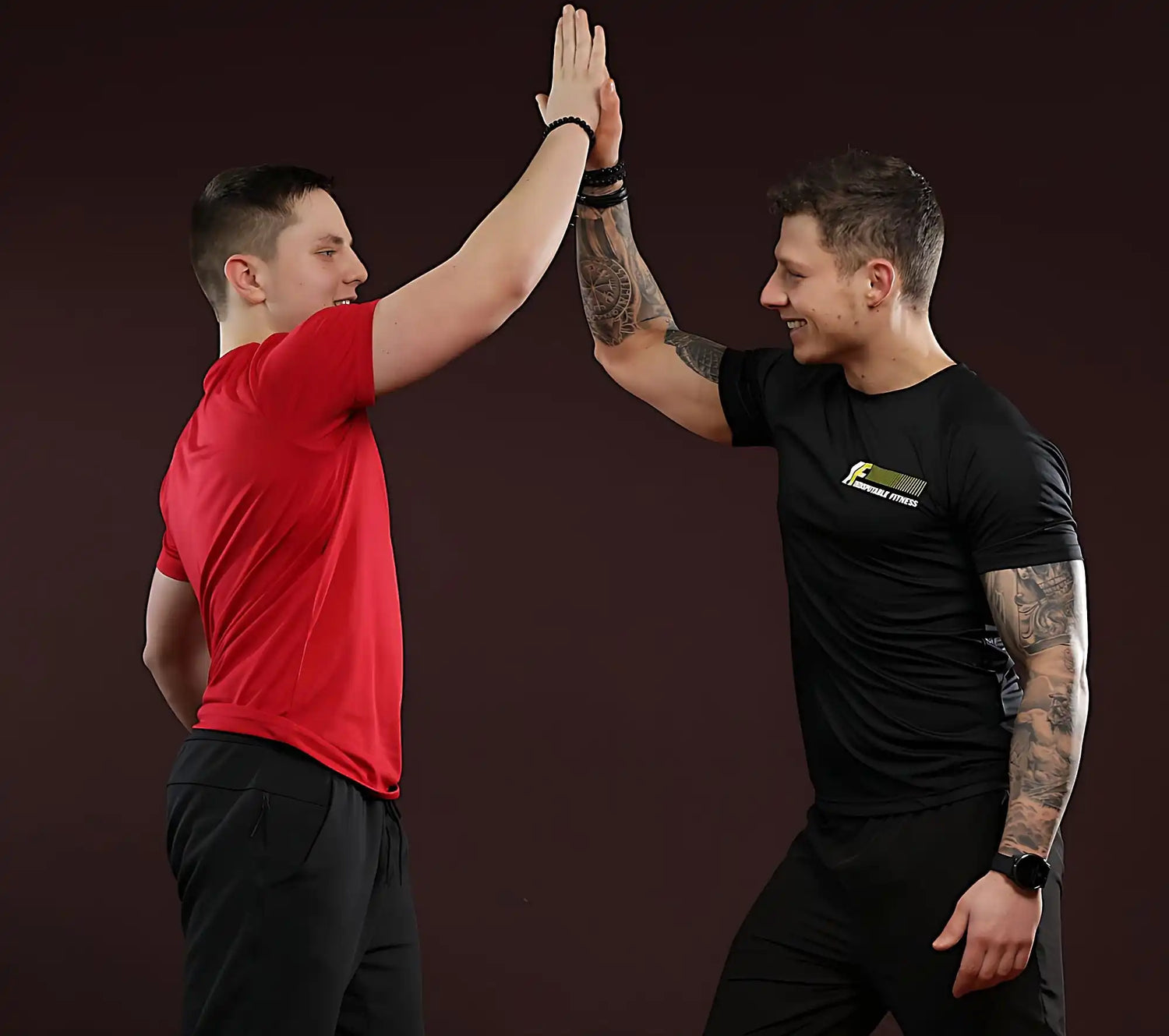 Two men giving each other a high-five while wearing contrasting red and black t-shirts.